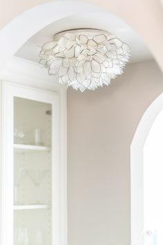 a white chandelier hanging from the ceiling in a dining room with pink walls