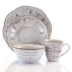 a white dinner set with two cups and saucers on the side, in front of a white background