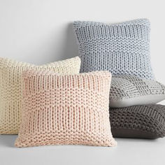 four knitted pillows in various colors and sizes