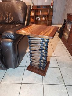 a stack of books sitting on top of a wooden table next to a leather chair