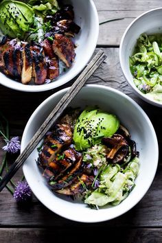 two bowls filled with meat, vegetables and chopsticks on top of a table