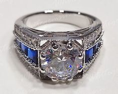 an antique style diamond and blue sapphire engagement ring with filigrees on the sides