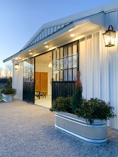 a white building with two large planters in front of it and lights on the side