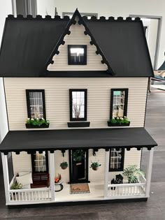 a doll house with black roof and white trim on the front porch, windows, and balconies