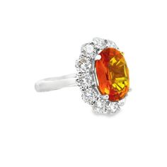 an orange and white diamond ring on a white background with the center stone surrounded by diamonds