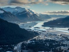 an aerial view of a town and mountains with snow on the ground in the foreground