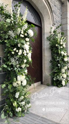 white flowers and greenery on the side of a building