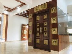 a large wooden door with gold decorations on the front and side panels in an empty room