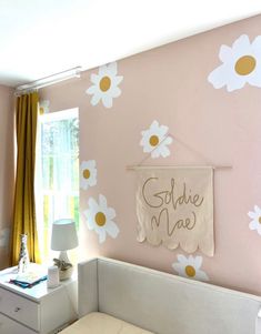 a baby's room decorated in pink and white with daisies on the wall