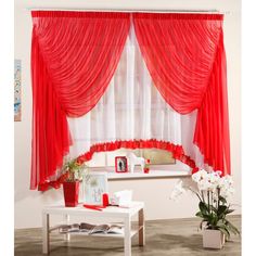 a living room with red drapes and white flowers in vases on the coffee table