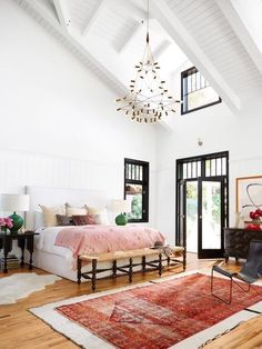 a bedroom with a large rug and chandelier hanging from the ceiling