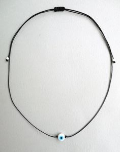 Evil eye necklace White and Turquoise eye bead Black string choker Mens evil eye Evil eye jewelry Protection amulet Minimalist Gift Simple This simple yet beautiful choker necklace is made using durable black waxed string and has a white glass bead evil eye in the middle,and seed beads at the ends. The diameter of the flat eye bead is 8mm approx. It is adjustable with a sliding knot closure. More string bracelets in my shop: https://www.etsy.com/shop/LuckyRatJewellery?ref=seller-platform-mcnav&a Adjustable Evil Eye Round Pendant Necklace, Minimalist Adjustable Single Strand Choker, Adjustable Evil Eye Choker Necklace, Adjustable Evil Eye Choker, Adjustable Evil Eye Choker Jewelry, Adjustable Round Evil Eye Necklace, Adjustable Evil Eye Amulet Necklace, Adjustable Evil Eye Spiritual Necklace, Adjustable Spiritual Evil Eye Necklace