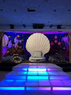 a large white shell sitting on top of a blue lit dance floor in front of an aquarium