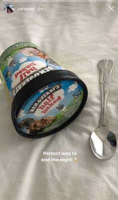 a cup and spoon sitting on top of a bed next to an empty container with dog treats in it