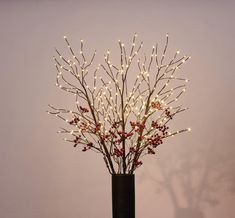 a vase filled with branches and lights on top of a table