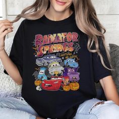 a woman wearing a black shirt that says radiator springs with cars and pumpkins