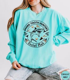 Discover our Shark Tooth Hunters Social Club Comfort Colors summer beach vacation crewneck Sweatshirt! This trendy high quality Unisex Shark Tooth Sweatshirt is Comfort Colors NEW light weight design! It is super soft and comfortable made of 100% ring-spun ethically grown cotton. It has a relaxed fit that is made of a light weight fabric. Looks super cute with shirts, jeans or size up 1 to 3 sizes for an oversized beach cover up. Great gift idea for a Birthday or a Shark lover! Comes in 14 prett Beachy Sweater, Beach Sweatshirt, Shark Gifts, Shark Lover, Summer Beach Vacation, Shark Shirt, Shark Tooth, Shark Teeth, Comfort Wear