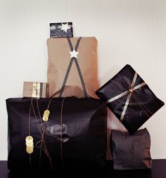 three wrapped presents sitting on top of a table next to brown paper bags and twine