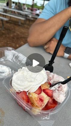 a plastic container with strawberries and whipped cream in it on top of a table