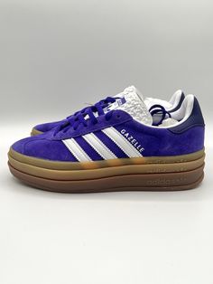 Elevate your sneaker game with these bold and stylish Adidas Women's Gazelle sneakers. With a unique color combination of purple and white, these sneakers are perfect for any fashion-forward woman. The suede upper material provides a comfortable and durable fit, while the W shoe width ensures a secure and supportive fit. These athletic sneakers are designed with a UK shoe size of 4 and a US shoe size of 5.5, making them a perfect fit for any woman in between these sizes. The Adidas Gazelle model is a classic and iconic sneaker that has been tried and tested over the years. Make a statement with these sneakers and step up your shoe game today. Purple Low-top Sneakers With Gum Sole, Sporty Purple Sneakers With Gum Sole, Purple Skate Shoes With Vulcanized Sole For Streetwear, Purple Vulcanized Sole Skate Shoes For Streetwear, Purple Custom Sneakers With Gum Sole For Sports, Purple Sporty Sneakers With Vulcanized Sole, Sporty Custom Purple Sneakers With Contrast Sole, Purple High-top Sneakers With Vulcanized Sole, Purple High-top Sneakers With Gum Sole