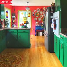 a kitchen with green cabinets and red walls, hardwood floors and an area rug on the floor