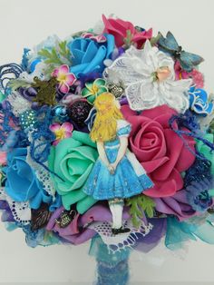 Alice in Wonderland Wedding Bridal  Bouquet Flowers-Bright and Colorful one of a kind bouquet--- The only one like it - our bouquets are -One of a kind- and not Repeated over and over Alice stands before her Rose Garden with the Beautiful Colors... she spots the Blue butterflies , and wonders where the Cheshire Cat is hiding this time..   A HANDMADE Fantasy Wedding Bouquet to keep forever--- ON ARRIVAL---Place in a tall clear vase away from SUN-ODORS-MOISTURE-- ADD MARBLES OR SEA GLASS FOR WEIGHT.. -the Bridal-Bride Bouquet Flowers are Bright Colors We are Professional Florists and Artist for over 37 years.. made with love !!  to cherish forever !! One of a Kind Wonderland Wedding Keepsake Bouquet with Alice in a  Whimsical colorful mixed rose Bouquet, Brooch's, textiles, laces, embroidere Through The Looking Glass Prom Theme, Tall Clear Vase, Alice In Wonderland Wedding Theme, Wonderland Wedding Theme, Dream Beach Wedding, Alice In Wonderland Wedding, The Cheshire Cat, Prom Theme, Clear Vase