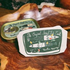 two tins sitting on top of a wooden table next to an object that reads the original land of fish