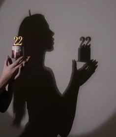 a woman holding a cake with the number twenty two on it in front of her face