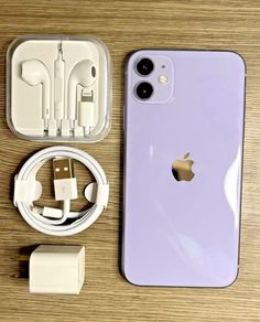 an iphone with ear buds, headphones and charger next to it on a table