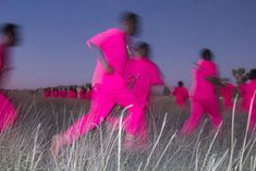 some people in pink are walking through the grass