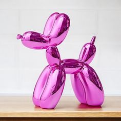 a pink balloon dog sitting on top of a wooden table