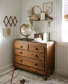 a dresser with a globe on top of it in a room that has striped walls