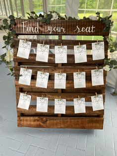 a wooden sign that says find your seat with notes pinned to it and greenery