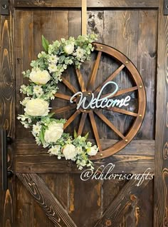 a wooden door with a wreath and welcome sign on the front, along with white flowers