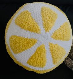 a yellow and white knitted fruit cushion sitting on top of a black table cloth