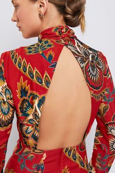 the back of a woman's red dress with an open neck and floral print