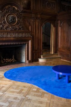 a blue coffee table sitting in front of a fire place on top of a wooden floor