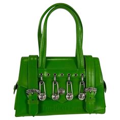 Presenting a fabulous bright green Gianni Versace safety pin mini bag, designed by Gianni Versace. A legendary creation from Gianni Versace's S/S 1994 collection, forever intertwined with Elizabeth Hurley's iconic 'Safety Pin' dress. This petite bag takes center stage with its striking silver metal Versace safety pins and Medusa logo. Adorned with two silver buckles, double magnetic closures, and delicate Versace Medusa reliefs, this bag is crafted from bright green leather. Its thoughtful design includes side pockets secured by Medusa closures and protective feet, ensuring a perfect balance of fashion and functionality. Approximate measurements: Height: 5.5" Width: 8.5" Depth: 3" Handle Drop: 5" Green Bag Outfit, Versace Safety Pin, Luxe Handbags, Pin Bag, Versace Bag, Versace Vintage, Vintage Versace, Elizabeth Hurley, Luxury Purses