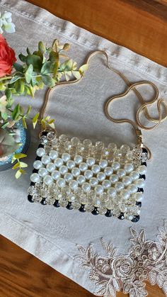 a white and black beaded purse sitting on top of a table next to flowers