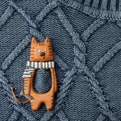 a wooden cat brooch sitting on top of a blue sweater