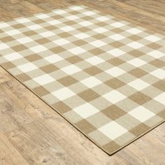 a brown and white checkered rug is on the floor in front of a wooden floor