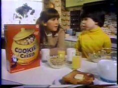 two women sitting at a table talking to each other with cookies in front of them