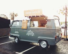 an old green truck is parked in a parking lot with the door open and some items on top