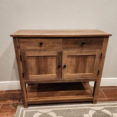 a wooden cabinet sitting on top of a tile floor next to a white wall and rug