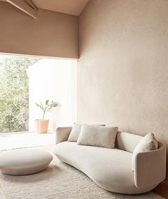 a white couch sitting on top of a rug in a living room next to a window