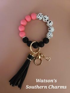 a bracelet with black, white and pink beads and a tasseled keychain