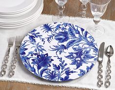 a blue and white plate sitting on top of a wooden table next to silverware