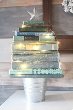 a stack of books sitting on top of a white table next to a christmas tree