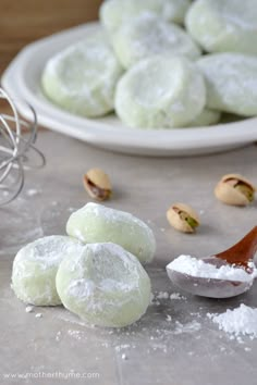 powdered sugar cookies on a table next to a bowl of pistachios