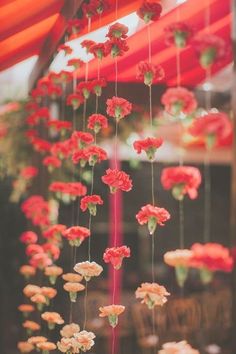 red and white flowers hanging from the ceiling in a room with an orange canopy over it